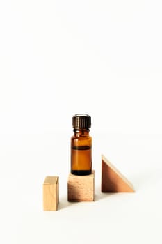 Bottle with aromatic oil standing on a wooden cube. Front view.