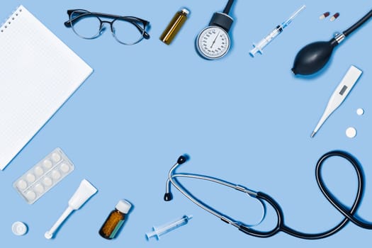 Medical blue background with different accessories: stethoscope, syringe and tablets.