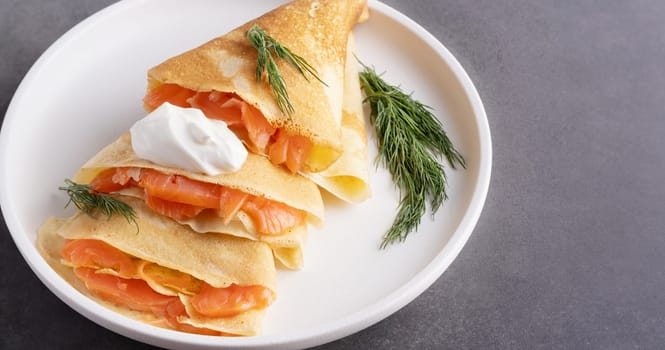 Pancakes with salmon, sour cream and greenstuff. Thin, not sweet blinchiki stuffed with red fish. Feast of Maslenitsa.