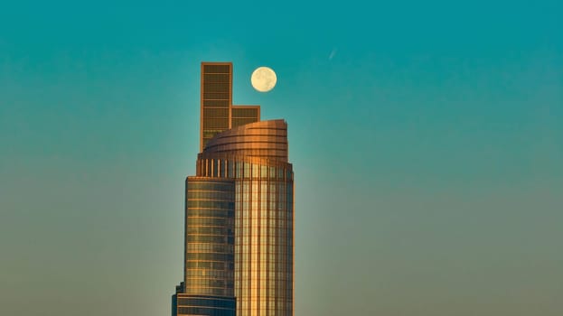 Image of Mystic moon over two skyscraper buildings with teal blue sky in aerial Chicago, IL