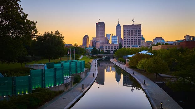 Serene Sunrise Over Indianapolis Skyline, Aerial View Captured by Drone, Showcasing Modern Architecture Reflecting on Tranquil River Canal