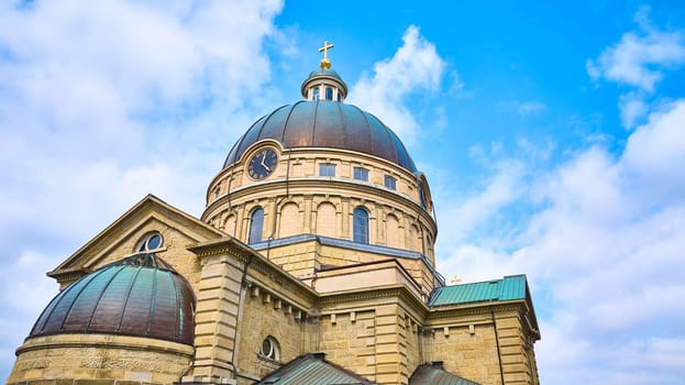 Majestic Basilica of St Josaphat in Milwaukee, Wisconsin, captured in 2023 by a DJI Mavic 3 drone, highlighting the structural grandeur, golden cross, and classical architecture under a serene blue sky.