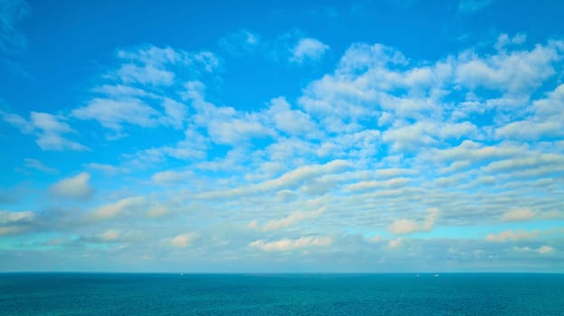 Image of Blue sky with wispy white clouds, dream and inspiration over blue Lake Michigan water, inspire
