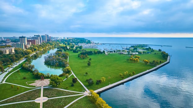 Aerial view of Milwaukee's urban park by Lake Michigan, showcasing autumn hues, tranquil water features, and a vibrant city skyline