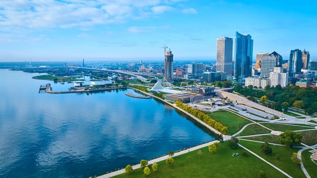 Aerial view of Milwaukee's skyline with modern skyscrapers reflecting sunlight, the iconic Quadracci Pavilion, and tranquil Lake Michigan, showcasing urban development and natural harmony.
