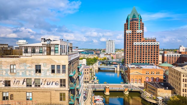 Sunny aerial view of Milwaukee's diverse architecture and riverfront, encompassing historical industry, modern skyscrapers, and recreational boating