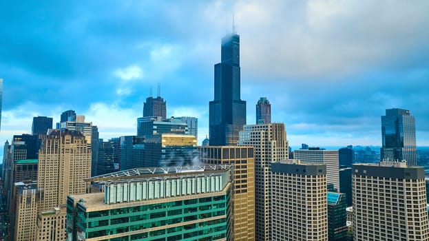 Image of Willis Tower soaring above Chicago downtown skyscraper buildings with gorgeous fog in tourism aerial