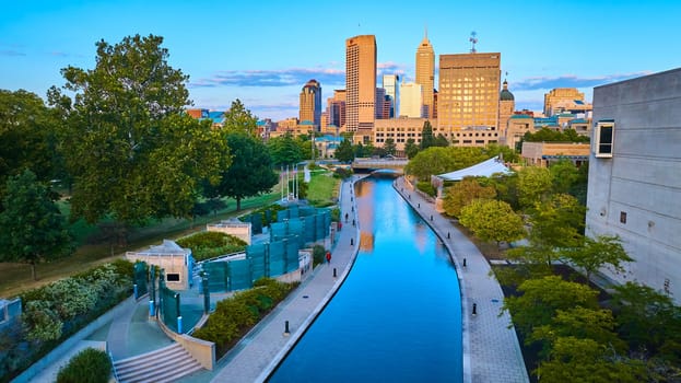 Golden Hour Over Indianapolis: Tranquil Canal Reflects Urban Skyline, Captured from Aerial View