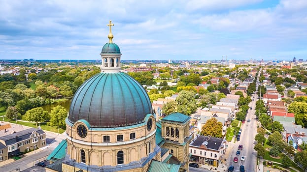 Aerial view of majestic Basilica of St Josaphat with a golden cross in Milwaukee, Wisconsin, showcasing historical architecture amidst a modern urban neighborhood, taken with DJI Mavic 3 drone