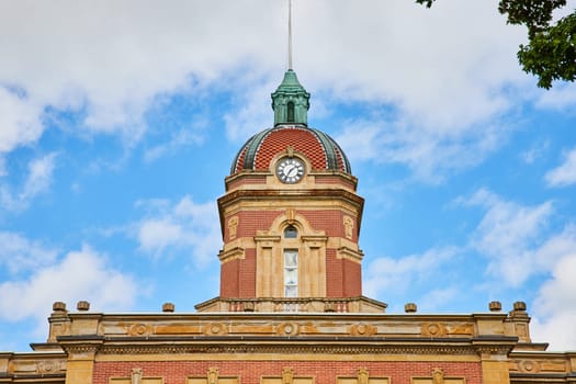 Image of Top of Elkhart County courthouse with clock on blue sky day with fluffy white clouds, summer, IN