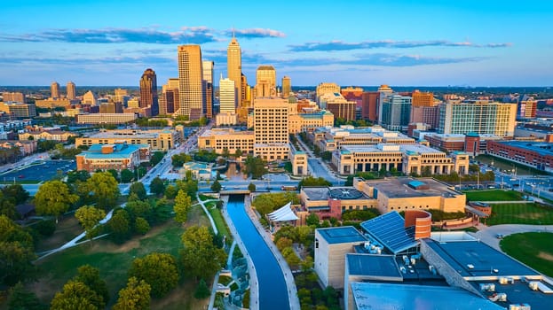 Golden Hour Glow Over Indianapolis: Aerial View Capturing Modern and Traditional Architecture, Serene Park, and Tranquil Canal