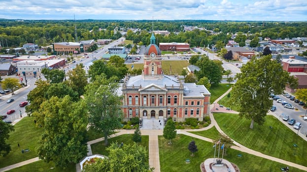 Aerial view of historic Elkhart County Courthouse with red brick facade and teal dome in Goshen, Indiana, showcasing small town charm and American heritage