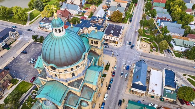 Aerial view of the historic Basilica of St Josaphat with its green dome and gold cross, nestled in a tree-lined urban landscape, Milwaukee, Wisconsin