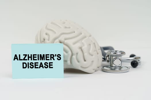 Medical concept. On a white surface next to the brain there is a stethoscope and stickers with the inscription - Alzheimers Disease