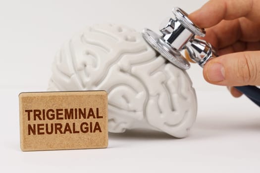 Medical concept. On a white surface, the brain is diagnosed using a stethoscope, next to it is a sign with the inscription - Trigeminal neuralgia