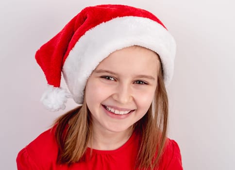 Little Girl In Red T-Shirt And Santa Hat Poses For A Festive Photo On A White Background