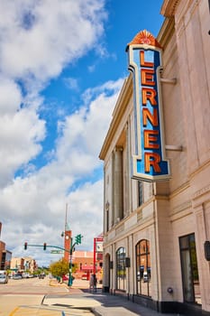 Daytime view of the historic Lerner Theater with its vibrant blue marquee in downtown Elkhart, Indiana, capturing the bustle of city life and architectural grandeur.