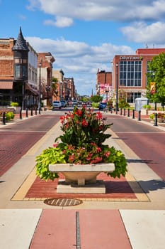 Vibrant street scene in Muncie, Indiana, 2023, showcasing community-oriented downtown with decorative planters, mixed architecture, and pedestrian-friendly layout.