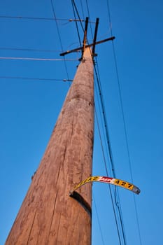 Vintage utility pole with weathered street sign under clear blue sky in downtown Muncie, Indiana, showcasing urban decay and power distribution system.