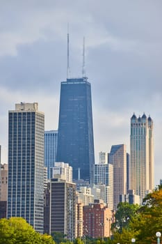 Image of Chicago skyscraper skyline above green trees, downtown buildings inviting tourism, travel in US
