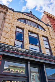 1885 sandstone building facade in downtown Muncie, Indiana, showcasing architectural heritage under a bright blue sky