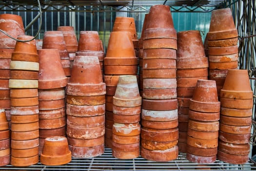 Organized terracotta pots on metal shelves at a greenhouse in Muncie, Indiana, 2023, showcasing rustic charm and gardening readiness.