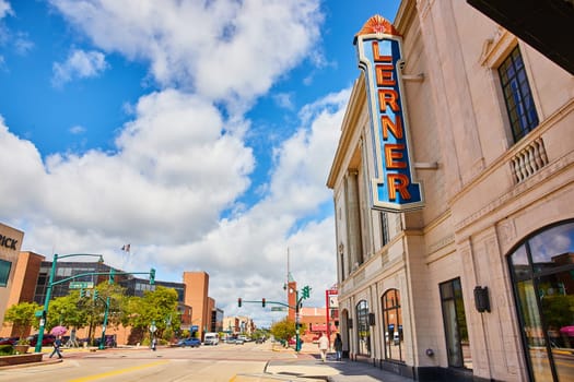 Bustling daytime scene in downtown Elkhart, Indiana, 2023, showcasing the vibrant blend of modern and historic architecture with the iconic Lerner theater marquee at the forefront.