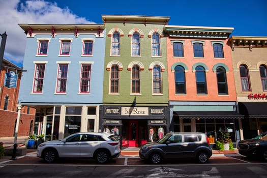 Vibrant street scene in downtown Muncie, Indiana featuring colorful Victorian-Italianate commercial buildings and modern cars, encapsulating a blend of history and urban life in 2023.
