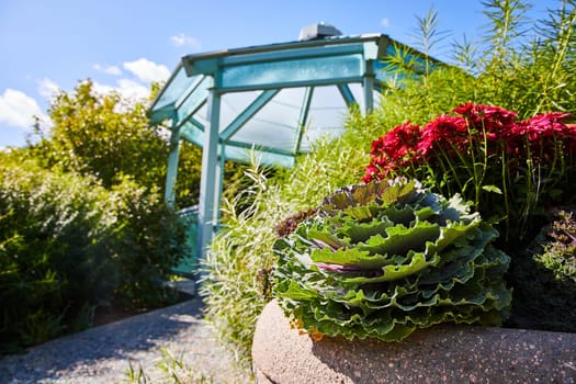 Bright ornamental garden with blooming plants and a charming turquoise greenhouse in Elkhart, Indiana's Botanic Gardens, 2023.