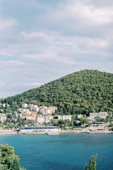 View from the sea of the Green Hills Hotel with a private pier on the bay at the foot of the mountain. Dubrovnik. Montenegro. High quality photo