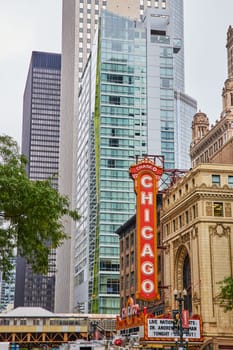 Image of Large orange sign with Chicago in white lettering in city with skyscrapers around it