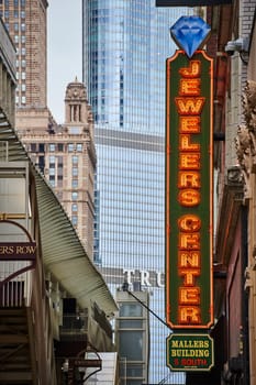Image of Chicago Jewelers Center yellow lights on sign beside train station with Trump Tower skyscraper