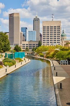 Sunny day in Indianapolis 2023, showcasing a tranquil canal amidst bustling skyscrapers, defining modern urban living.