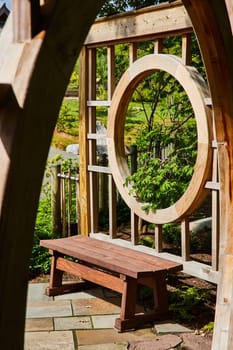 Serene Botanic Garden in Elkhart, Indiana, featuring a captivating wooden bench and circular gate, inviting relaxation amid lush greenery, 2023.