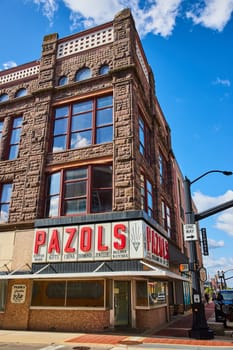 Vintage corner jewelry store Pazols in downtown Muncie, Indiana featuring brownstone architecture and large windows under a clear daytime sky.