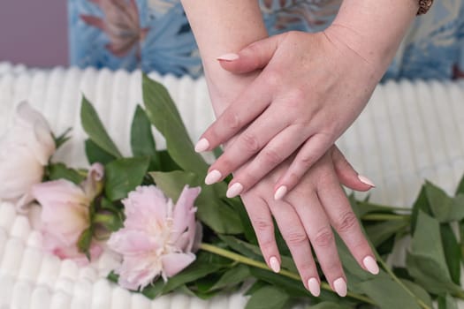 female hands with a beautiful peach manicure design, color 2024, pastel colors, delicate spring dewy peonies in the hands of a model, high quality photo
