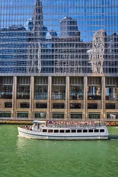 Image of Tourist cruise tour boat on Chicago canal with reflective building showing blue sky and skyscrapers