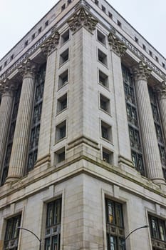 Image of Corner of grey building with pillars and columns on overcast day with gloomy, ominous sky, Chicago