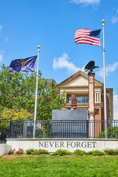 Patriotic Memorial in Indianapolis with Eagle Sculpture, 'Never Forget' Inscription, and U.S. Flags