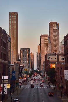 Image of Chicago skyscraper buildings with sunset lighting and blue sky over busy street, Illinois