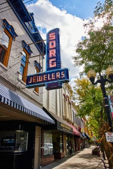 Image of Goshen Indiana street with shops on sunny summer day and old retro sign attached to building