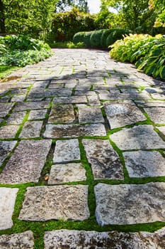 Stunning stone walkway through a lush, well-manicured garden in Botanic Gardens, Elkhart, Indiana, evoking tranquility and natural beauty.