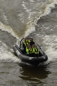 Vertical view of people with green life jackets in the RIB speedboat on the waves on the Elbe at Hamburg, Germany