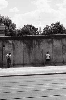 Vertical shot of people in front of the old Berlin Wall with Berlin TV Tower in Germany