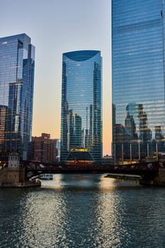 Image of Chicago canal at dawn with light reflecting blue off skyscraper windows and waterway, tourism USA
