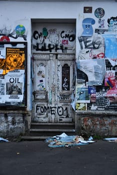 Vertical shot of the old front door and wall covered all over with graffiti and posters in Leipzig, Germany