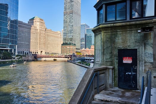 Image of No trespassing door on castle like tower overlooking Chicago canal with boats on water on sunny day