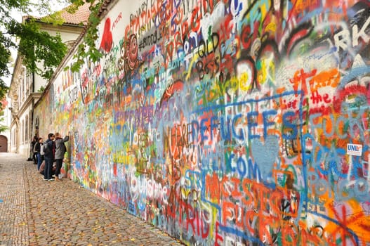 Group of young people paint a graffiti on the John Lennon Wall in Prague, Czech Republic