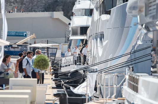 Monaco, Monte Carlo, 28 September 2022 - Invited wealthy clients inspect megayachts at the largest fair exhibition in the world yacht show MYS, port Hercules, yacht brokers, sunny weather. High quality photo