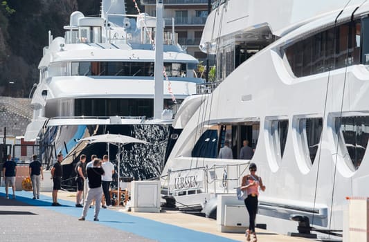 Monaco, Monte Carlo, 28 September 2022 - Invited wealthy clients inspect megayachts at the largest fair exhibition in the world yacht show MYS, port Hercules, yacht brokers, sunny weather. High quality photo